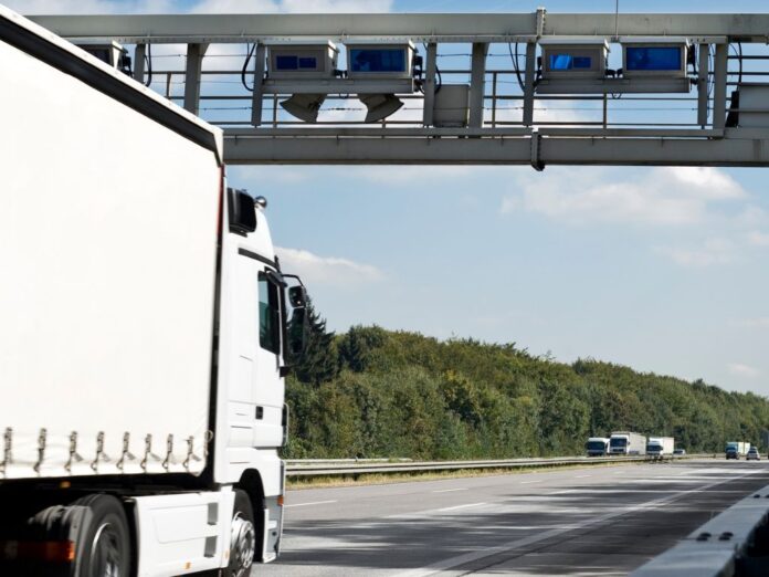 Caminhão em rodovia utilizando sistema de pedágio digital, ilustrando a tecnologia de pagamento automático e gestão de frotas.